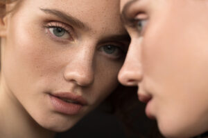 beautiful emotional woman with natural make up looking at the mirror