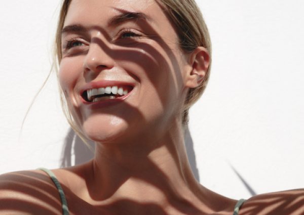 young woman with shadow of palm leaves on white wall